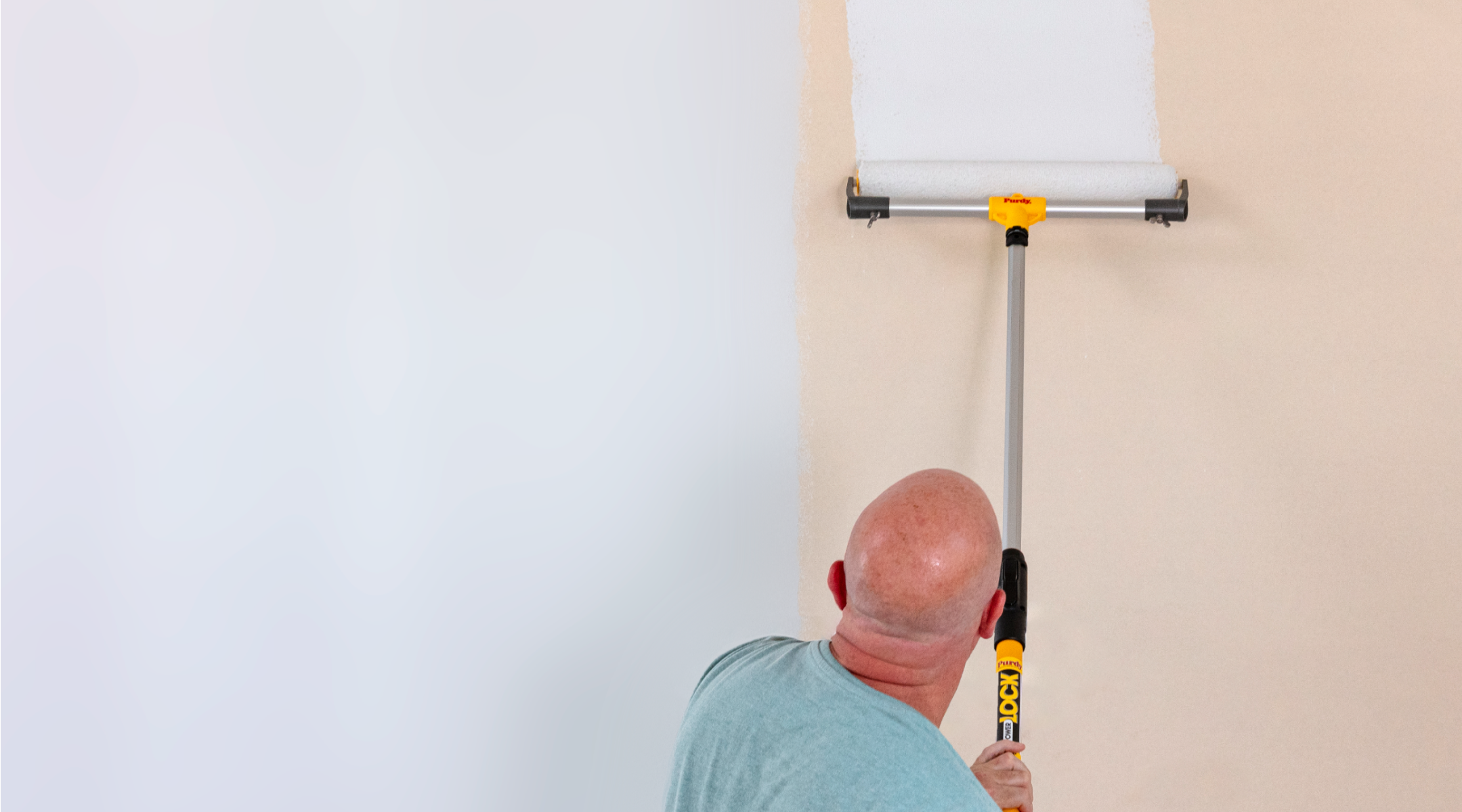 Pro painter covering a large wall with an eighteen-inch roller.