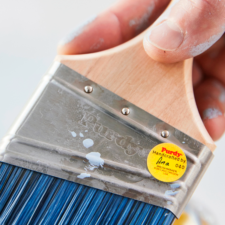 Closeup of a Pro painter holding a Purdy Pro-Extra brush with a signature yellow sticker.